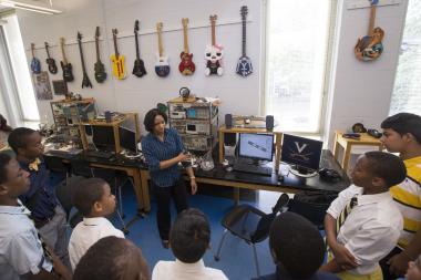 Intern Shunafrica White, center, tells a group of area middle school students with the M-Cubed program ("Math, Men and Mission") about her research improving upon a robotic arm.